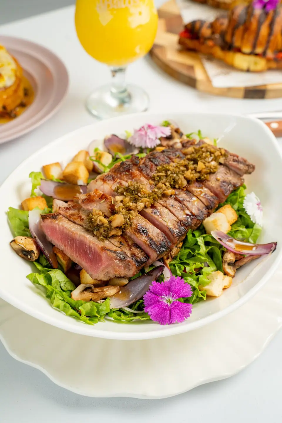 Salad with sliced sirloin and edible flowers