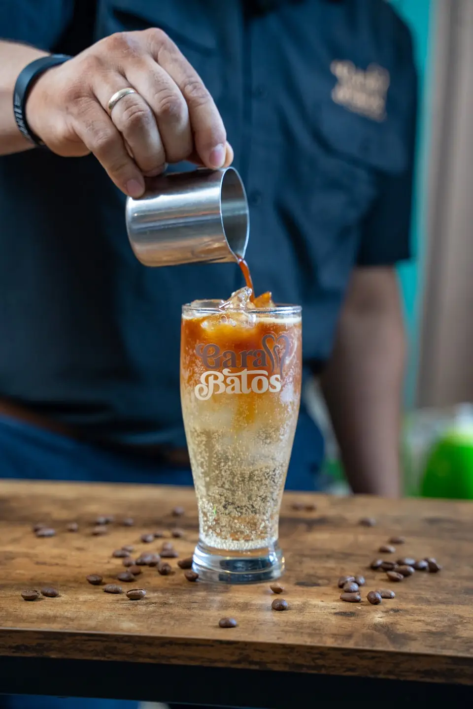 Barista pouring coffee over iced milk in a Garabatos glass